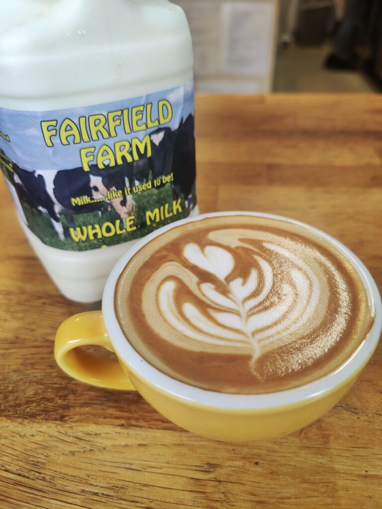 Fair Field farms milk bottle with a flat white coffee in a yellow cup